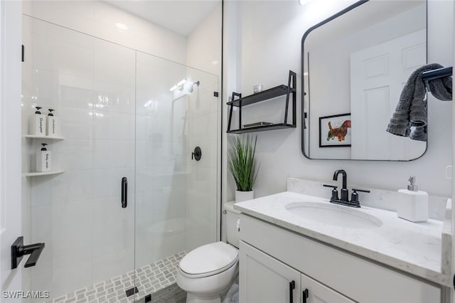 bathroom featuring toilet, a shower with door, and vanity