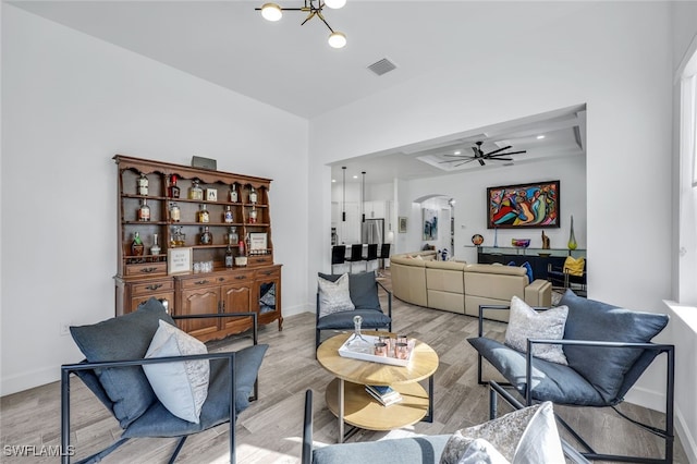 living room with ceiling fan with notable chandelier and light hardwood / wood-style floors