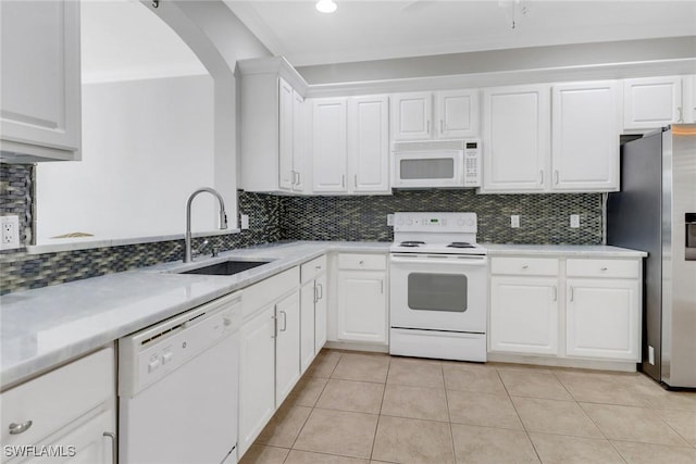 kitchen with white appliances, white cabinets, a sink, backsplash, and light tile patterned flooring