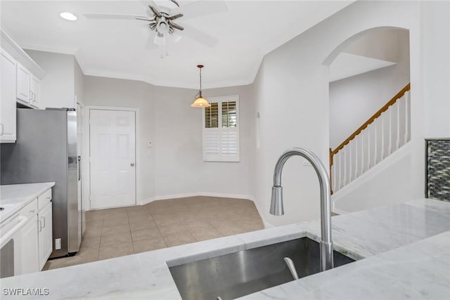 kitchen with crown molding, white cabinets, a sink, and light tile patterned floors