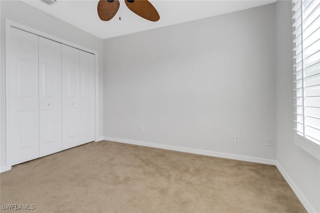 unfurnished bedroom featuring light carpet, visible vents, a ceiling fan, baseboards, and a closet