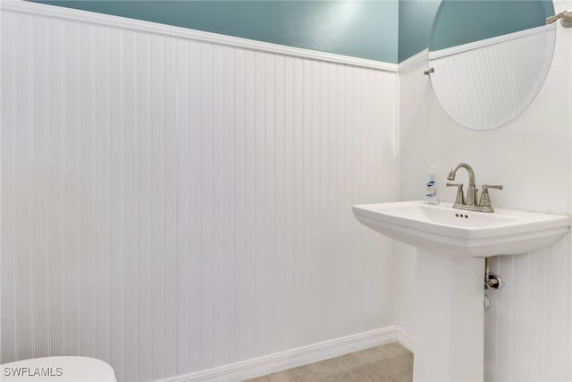 bathroom with a wainscoted wall, a sink, toilet, and tile patterned floors