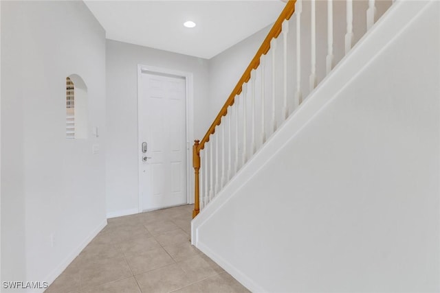 entrance foyer with arched walkways, light tile patterned flooring, recessed lighting, baseboards, and stairs