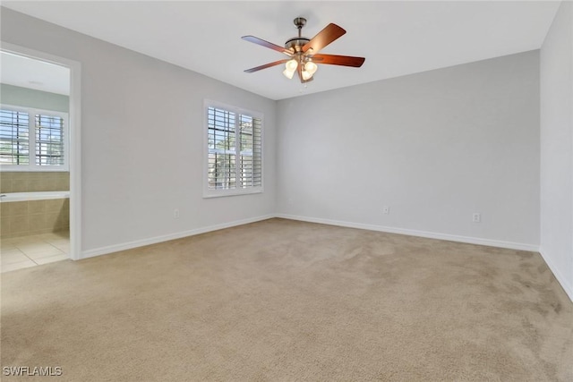 carpeted spare room with a healthy amount of sunlight, ceiling fan, and baseboards