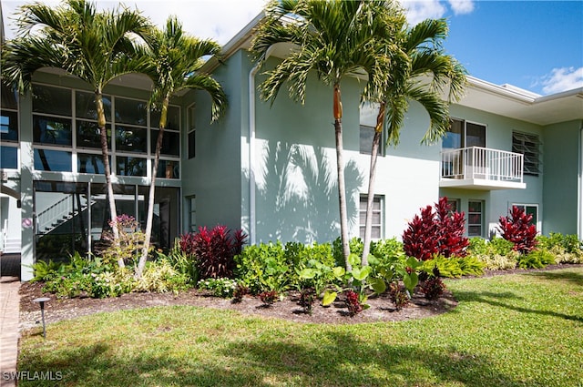 view of side of home with a lawn and a balcony