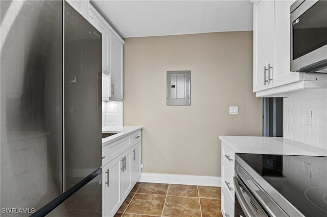 kitchen with white cabinetry, backsplash, stainless steel appliances, dark tile patterned floors, and electric panel