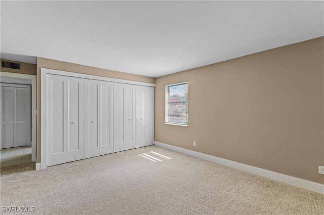 unfurnished bedroom with light carpet and a closet