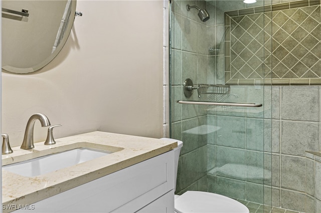 bathroom featuring vanity, a shower with shower door, and toilet