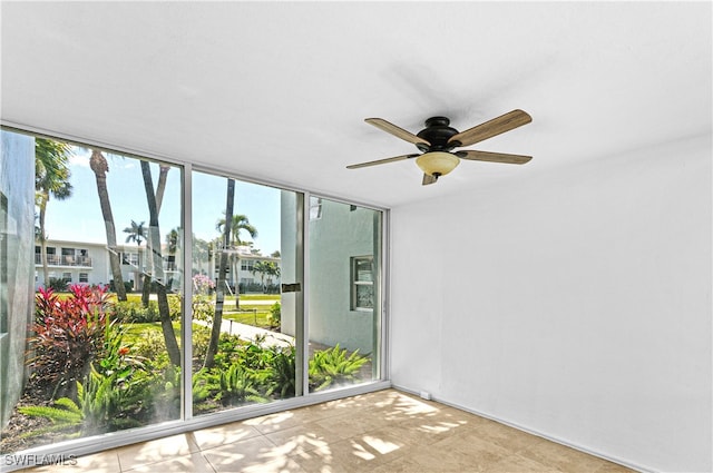 empty room with floor to ceiling windows, ceiling fan, and a wealth of natural light