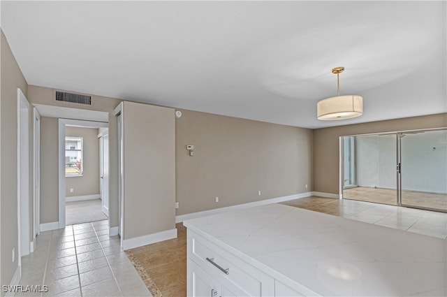 interior space with pendant lighting, white cabinetry, and light tile patterned flooring