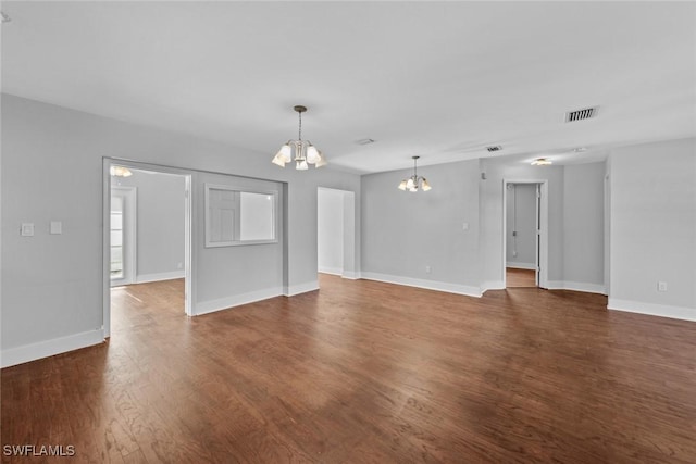 unfurnished living room with an inviting chandelier and dark hardwood / wood-style floors