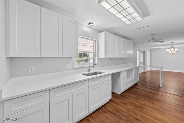 kitchen featuring ceiling fan with notable chandelier, dark hardwood / wood-style floors, sink, and white cabinets