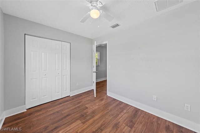 unfurnished bedroom with dark wood-type flooring, a textured ceiling, ceiling fan, and a closet