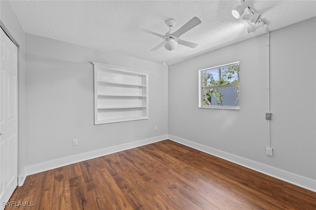 spare room with ceiling fan, built in features, wood-type flooring, and a textured ceiling