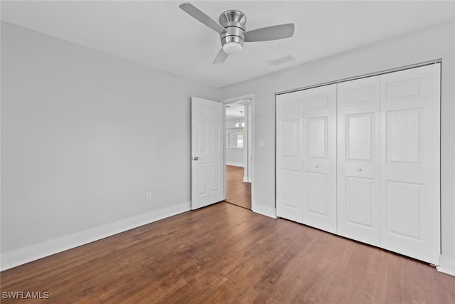 unfurnished bedroom featuring ceiling fan, dark hardwood / wood-style flooring, and a closet