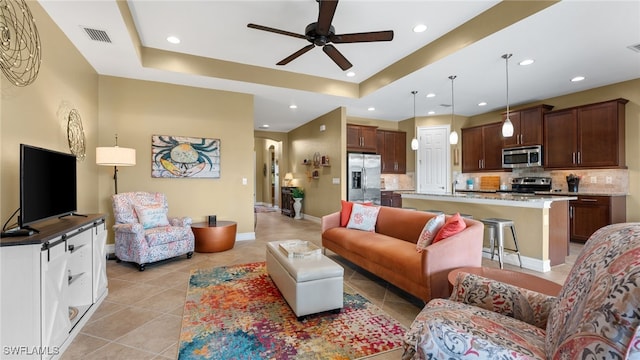 tiled living room featuring a tray ceiling and ceiling fan