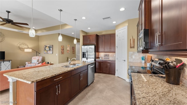 kitchen with appliances with stainless steel finishes, backsplash, ceiling fan, a kitchen island with sink, and sink