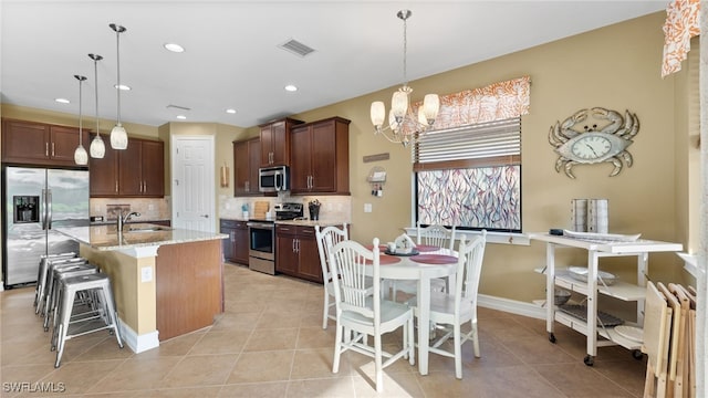 kitchen featuring sink, stainless steel appliances, pendant lighting, a kitchen island with sink, and a breakfast bar