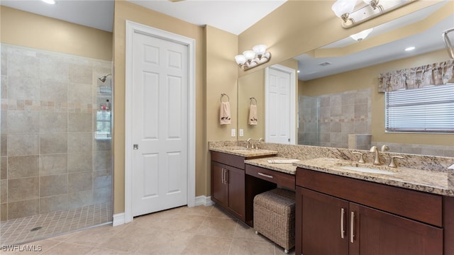 bathroom with tile patterned flooring, vanity, and tiled shower