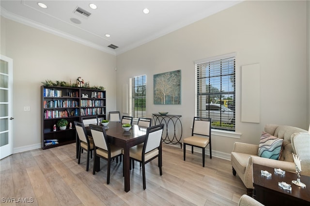 dining space with ornamental molding and light hardwood / wood-style flooring