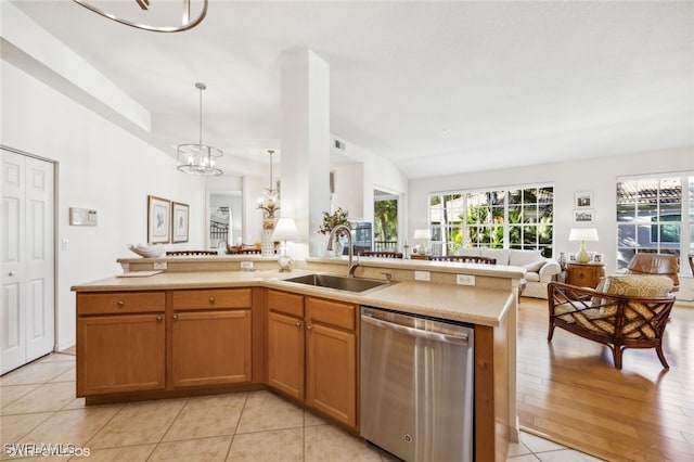 kitchen featuring sink, light tile patterned floors, dishwasher, a kitchen island with sink, and hanging light fixtures