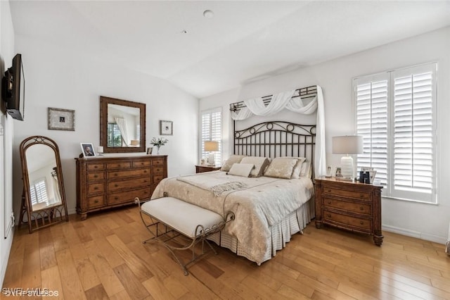 bedroom featuring multiple windows, vaulted ceiling, and light hardwood / wood-style flooring