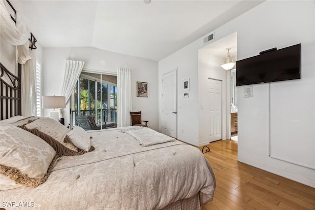 bedroom with vaulted ceiling, hardwood / wood-style floors, and access to exterior