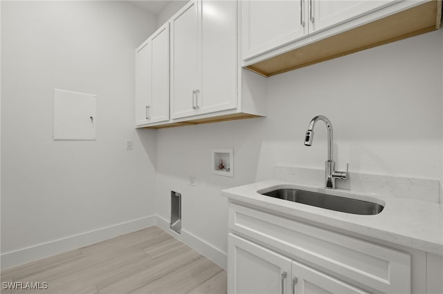 washroom featuring hookup for a washing machine, sink, light wood-type flooring, electric dryer hookup, and cabinets