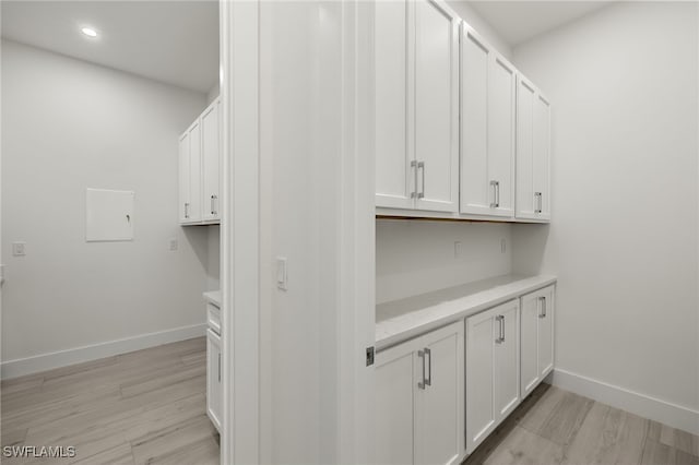 bar with white cabinetry and light hardwood / wood-style flooring