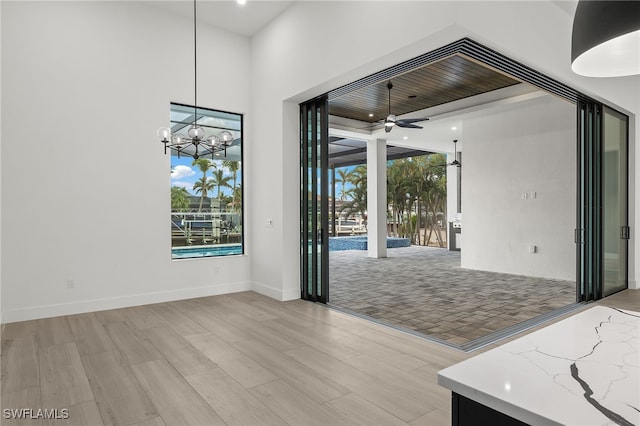 unfurnished dining area with ceiling fan with notable chandelier and light wood-type flooring