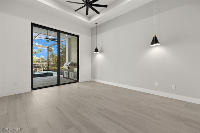 spare room with light hardwood / wood-style floors, a tray ceiling, and ceiling fan