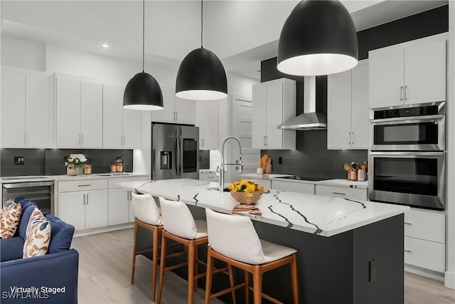 kitchen featuring white cabinets, tasteful backsplash, hanging light fixtures, an island with sink, and stainless steel appliances