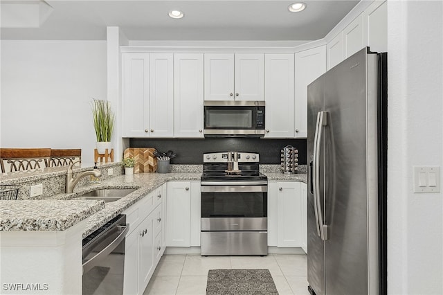 kitchen with sink, light tile patterned floors, light stone counters, white cabinetry, and stainless steel appliances