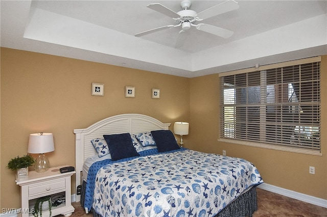 carpeted bedroom with a raised ceiling and ceiling fan