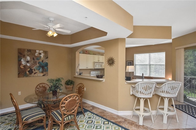 dining area featuring ceiling fan, light tile patterned flooring, and sink