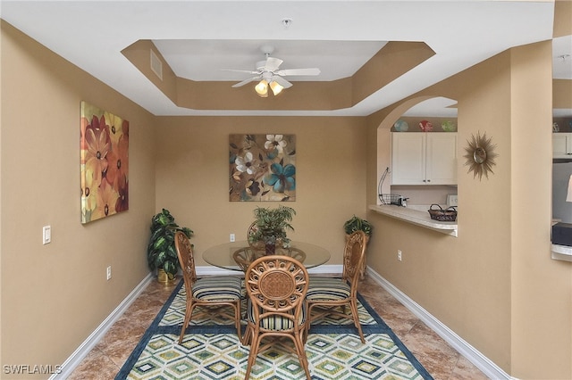 dining room with ceiling fan and a tray ceiling