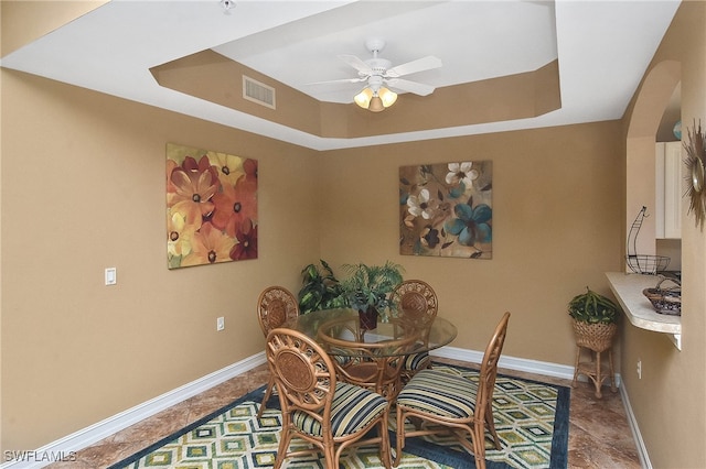 dining room with ceiling fan and a tray ceiling