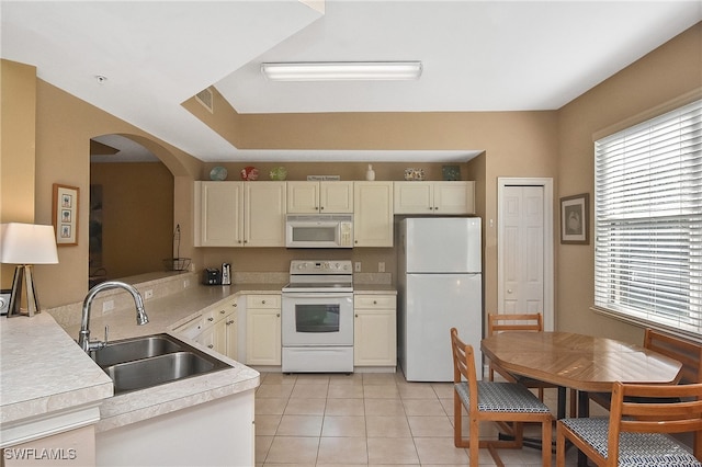 kitchen featuring light tile patterned floors, cream cabinets, sink, and white appliances