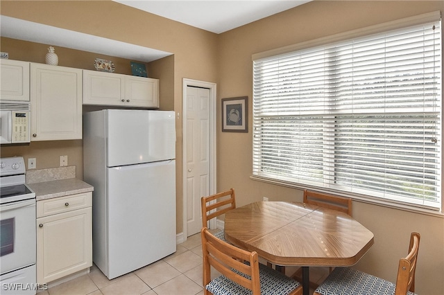 kitchen featuring white appliances, white cabinetry, and light tile patterned floors