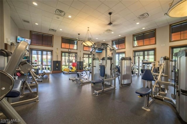 gym featuring a towering ceiling and a paneled ceiling