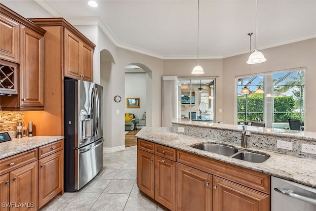 kitchen featuring light stone counters, stainless steel appliances, hanging light fixtures, and ornamental molding