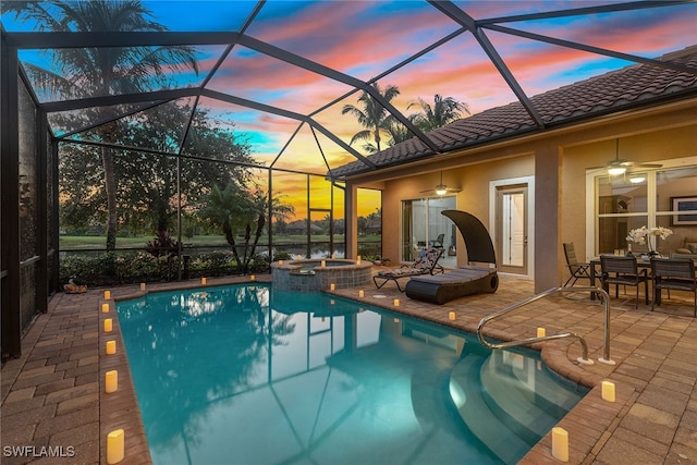 pool at dusk with a lanai, a patio, and an in ground hot tub