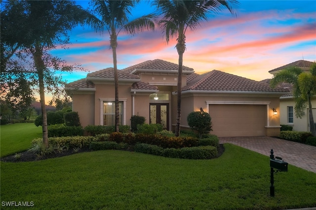 mediterranean / spanish-style home featuring a garage and a lawn