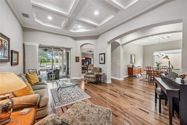 living room with light wood-type flooring, a notable chandelier, beam ceiling, coffered ceiling, and ornamental molding