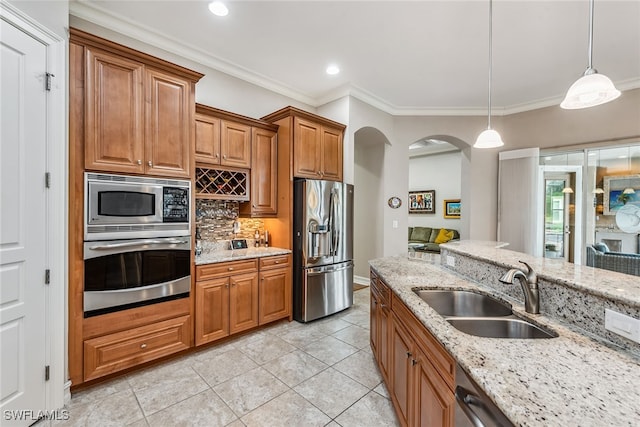 kitchen featuring pendant lighting, sink, ornamental molding, stainless steel appliances, and light stone countertops