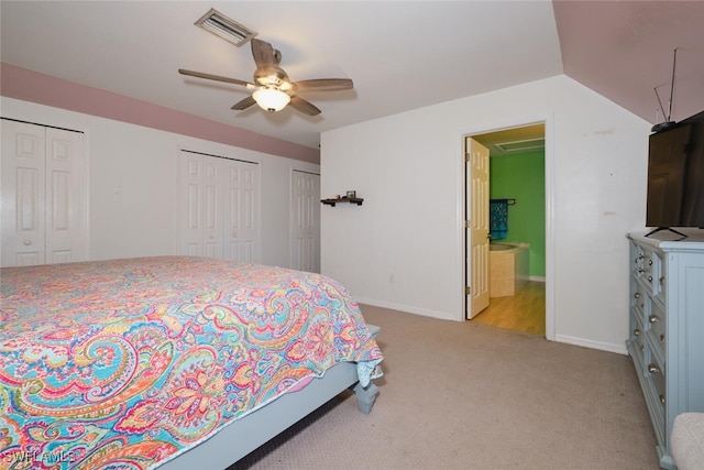 bedroom with connected bathroom, lofted ceiling, ceiling fan, two closets, and light colored carpet