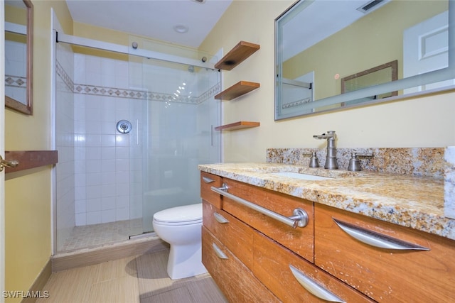 bathroom with vanity, toilet, and a shower with door