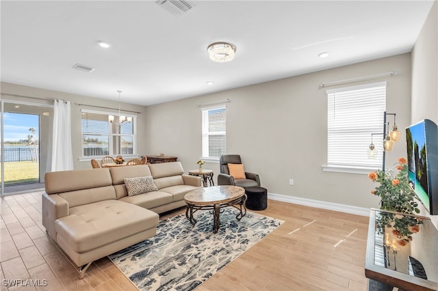 living room featuring light hardwood / wood-style floors, a healthy amount of sunlight, and an inviting chandelier