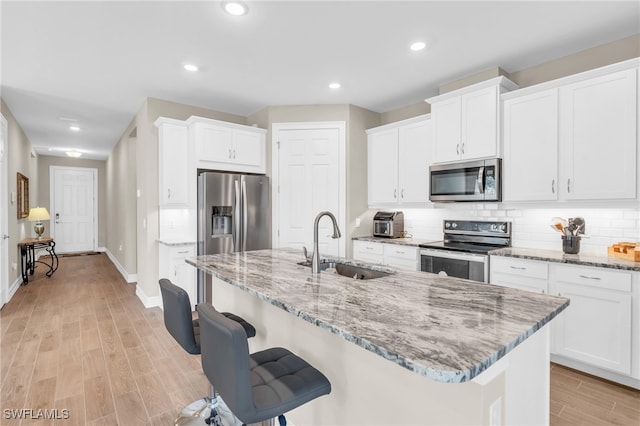 kitchen featuring white cabinetry, appliances with stainless steel finishes, sink, and a center island with sink