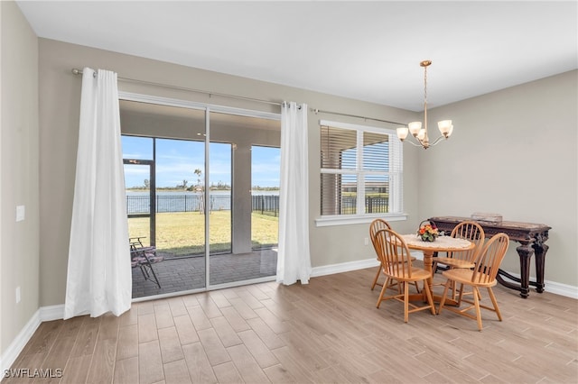 dining space featuring light hardwood / wood-style floors, a notable chandelier, and a water view